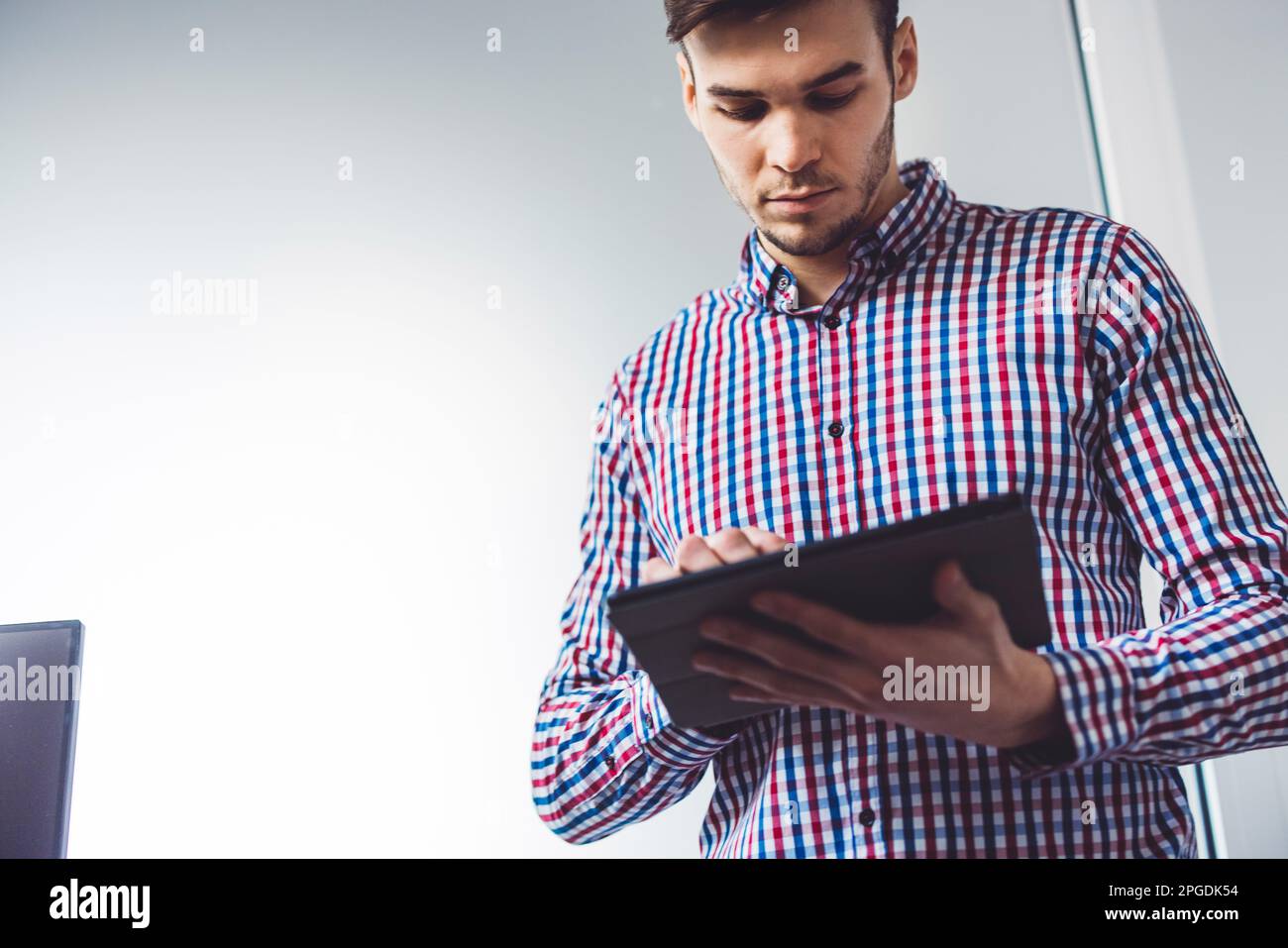 Low angle view, waist up young man a programmer working on the go, using his digital tablet  Stock Photo