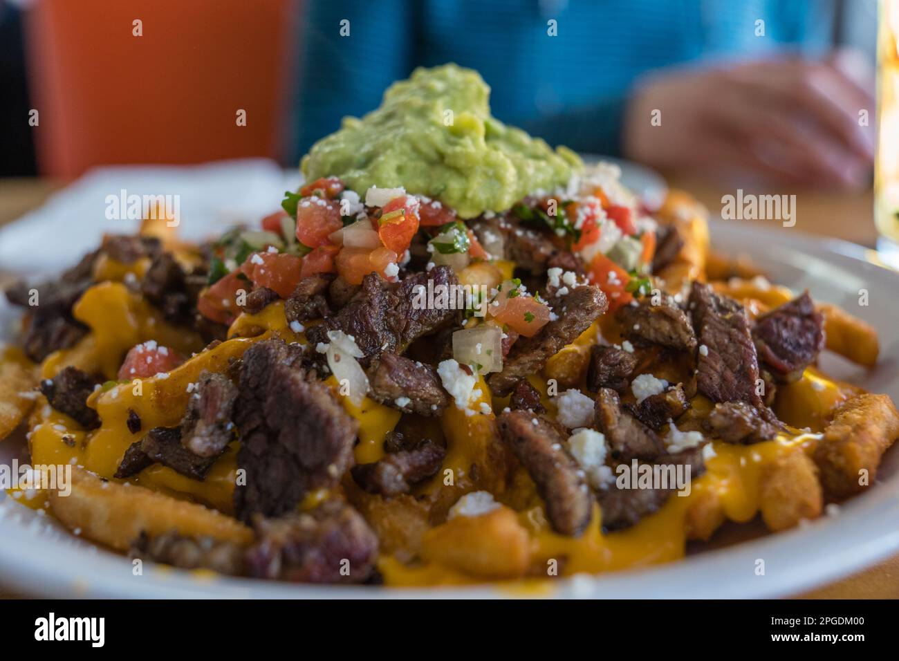 Close-up of a plate of carne asada fries with guacamole on top. This is a local speciality of parts of Arizona and the San Diego area of California. Stock Photo