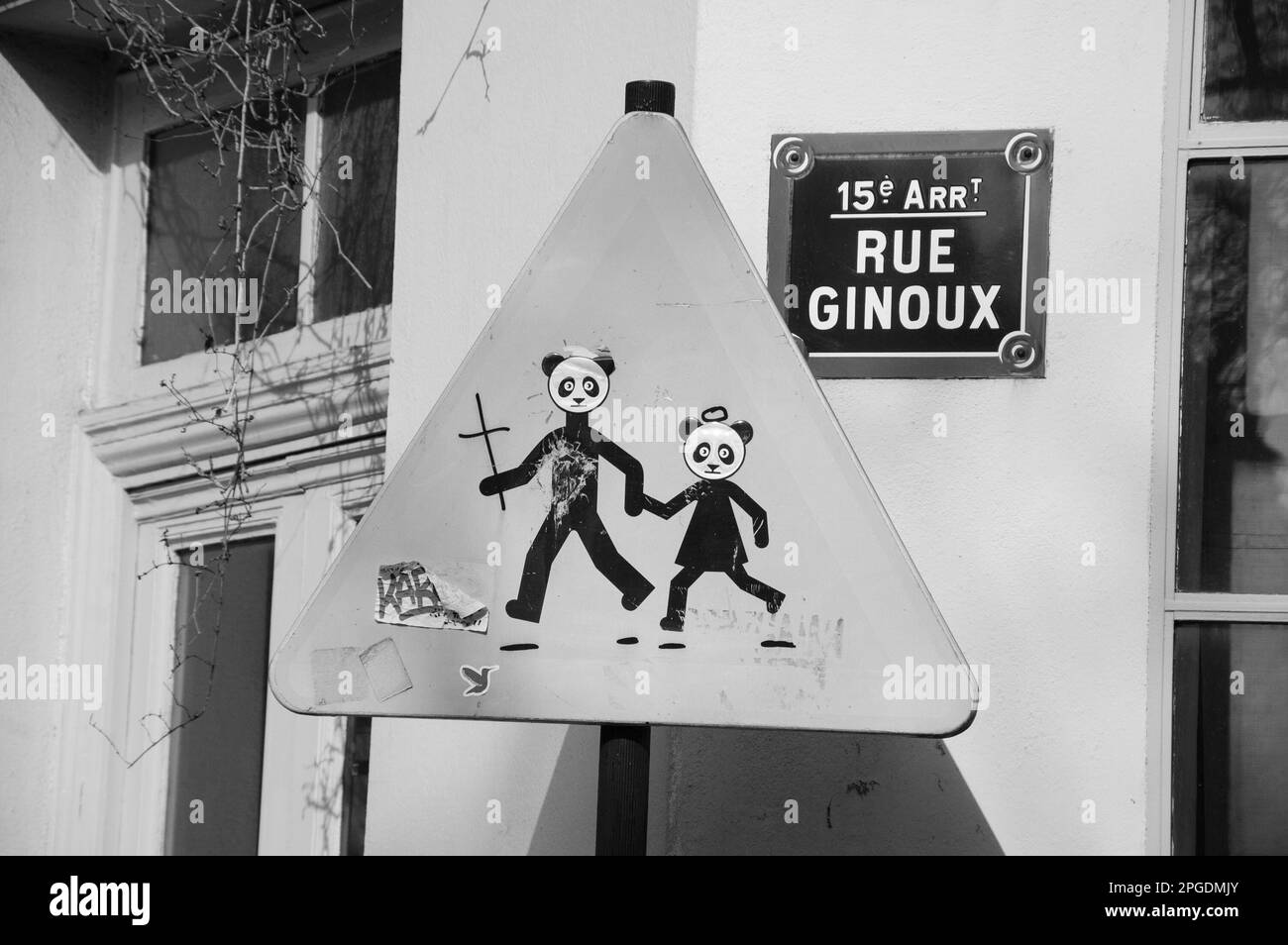 Paris, France - March 12, 2016: City life. Saint Panda bears crossing road. Traffic road sign Warning Children Crossing funny 'corrected'. Stock Photo