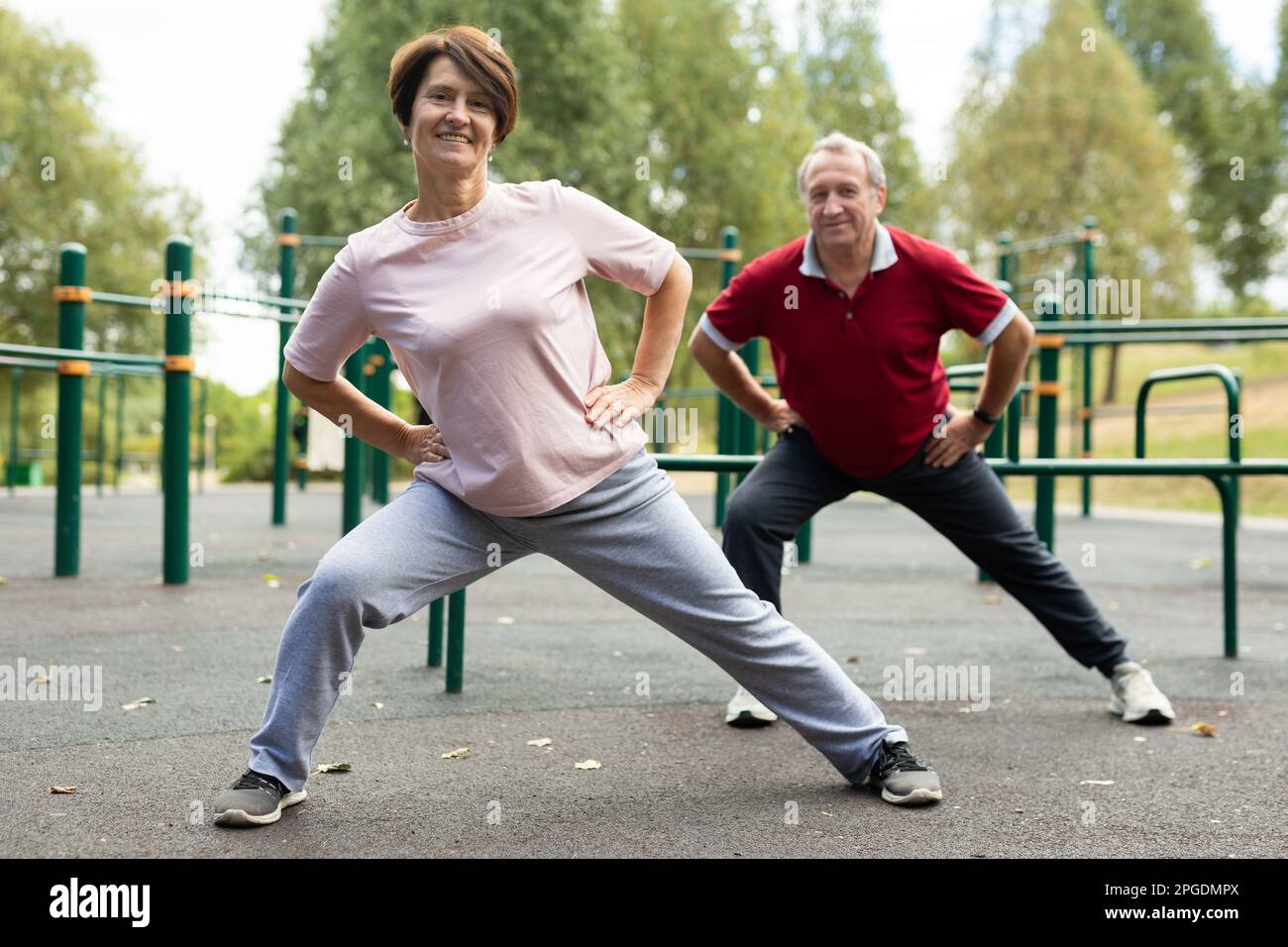 Aged man and woman practicing gymnastics in open-air sports area Stock ...