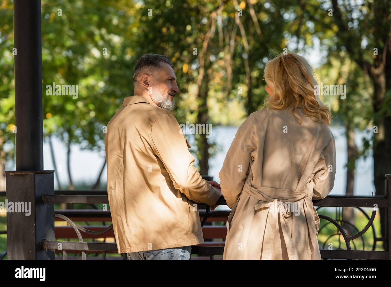 Smiling mature man talking to wife near bridge in spring park,stock image Stock Photo