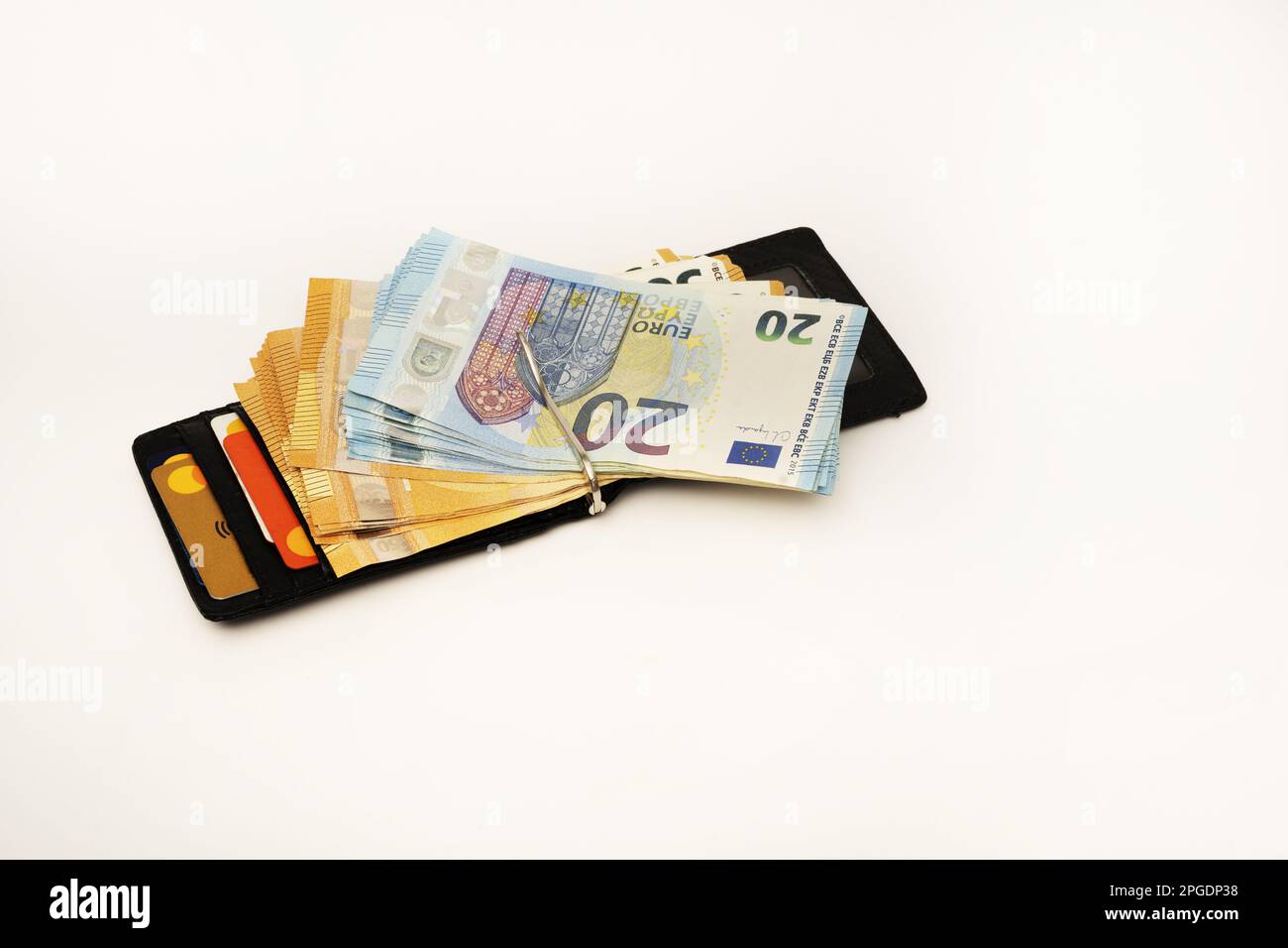 Carbon fiber men's wallet and a good wad of twenty and fifty euro bills along with some credit cards in their compartments Stock Photo