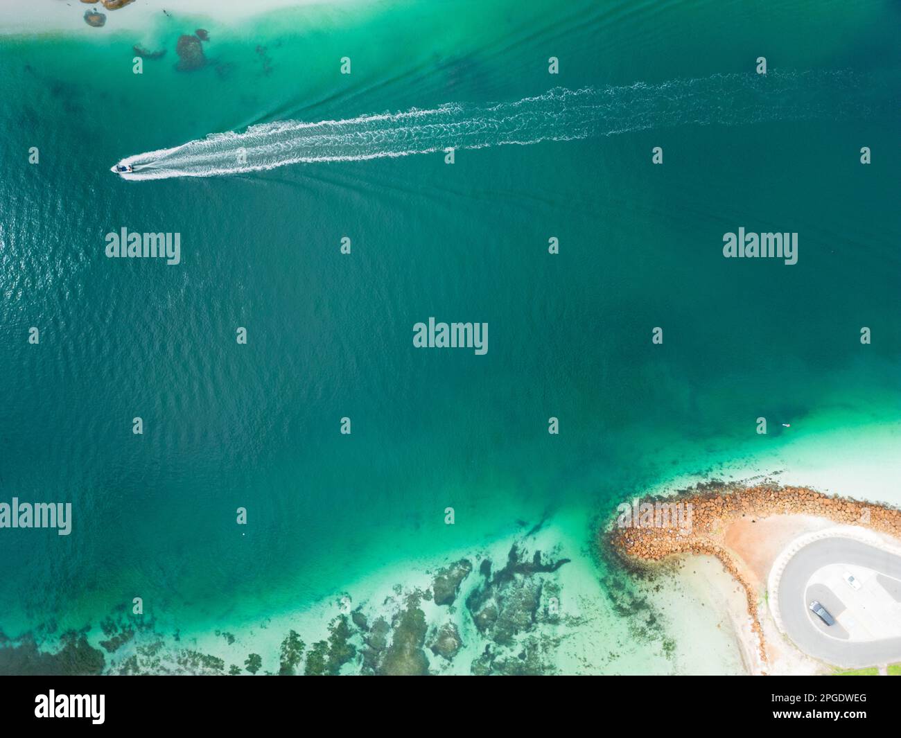 An aerial view of a boat navigating a picturesque lake, leaving a trail ...
