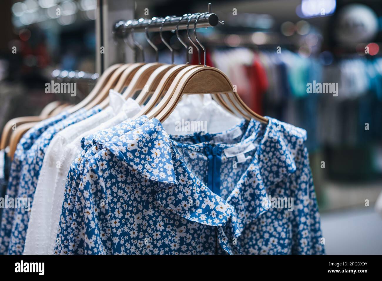 Blue women's dresses with floral pattern hanging on a hanger in a row. Summer fashion collection Stock Photo