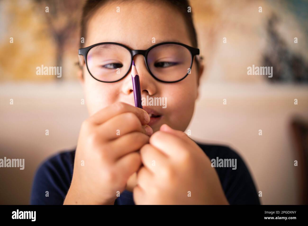 Smart young Asian boy wearing glasses squints at the pencil. The vision diseases problem. Stock Photo