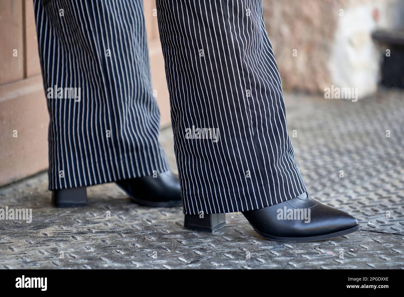 Woman's legs in stripped pants and closed black shoes Stock Photo