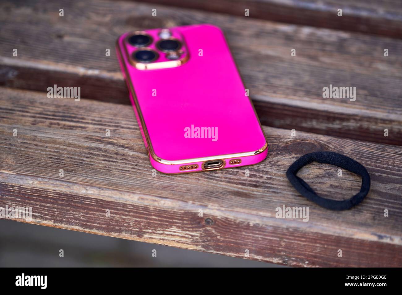 Pink cellphone and hair holder on the wooden bench Stock Photo