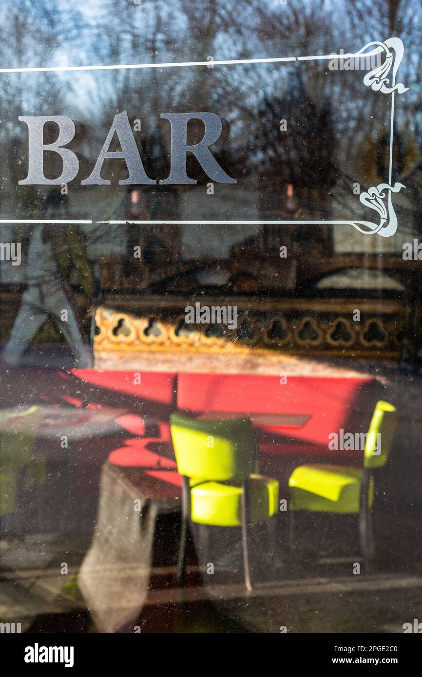 In a closed bar, green chairs and a red bench lit by the morning sun. Brussels. Stock Photo