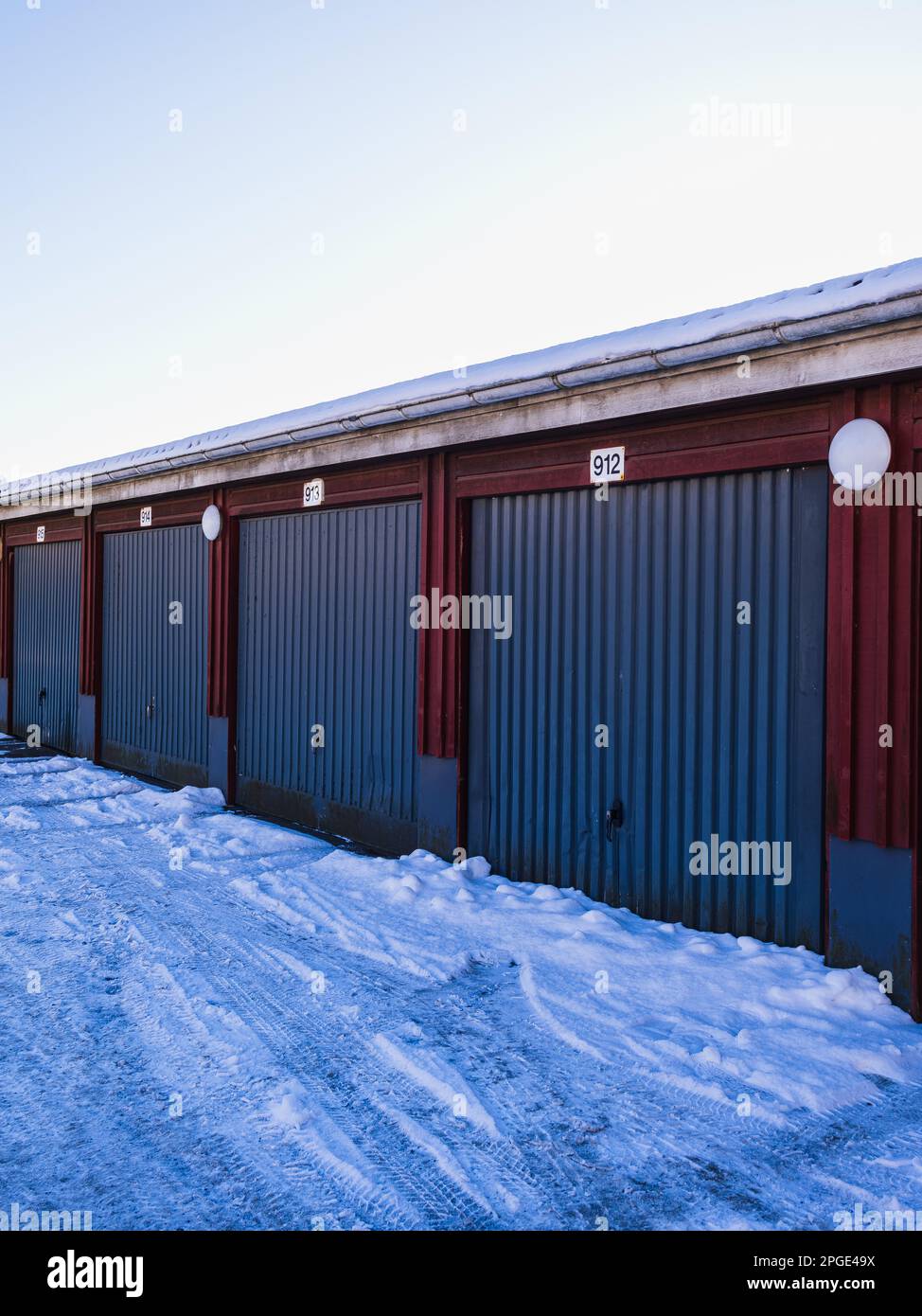 Rows of colorful garages in Sweden, blanketed by the fresh snowfall on a cold winter day beneath clear blue skies. Stock Photo