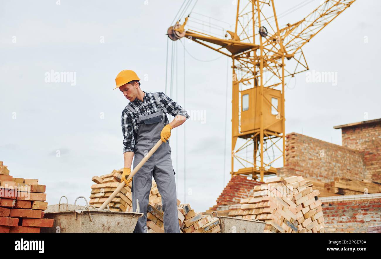 Using shovel with wooden holder. Construction worker in uniform and