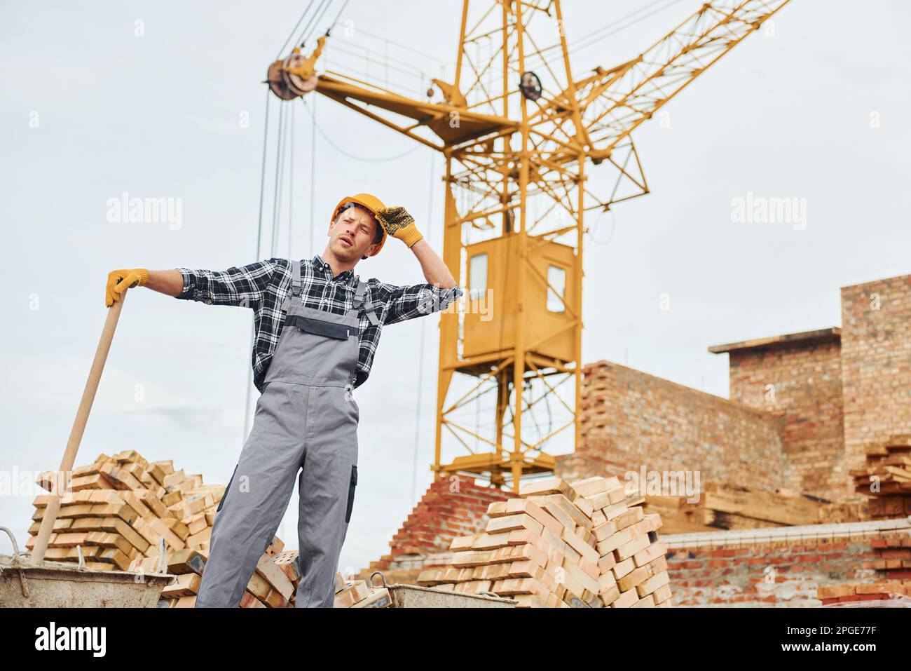 Using shovel with wooden holder. Construction worker in uniform and