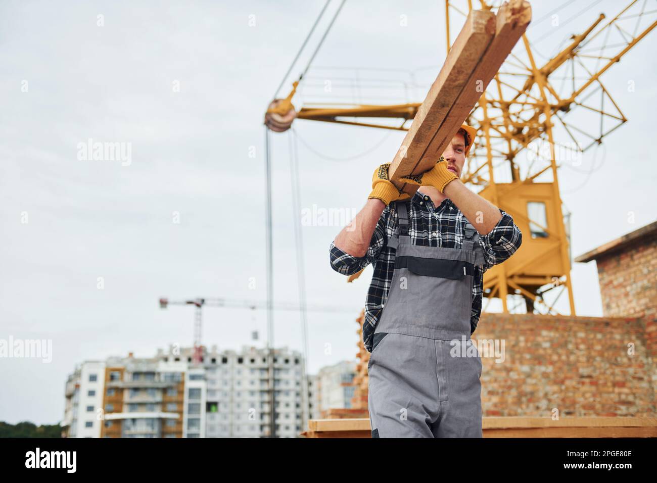 Transporting wooden boards. Construction worker in uniform and safety