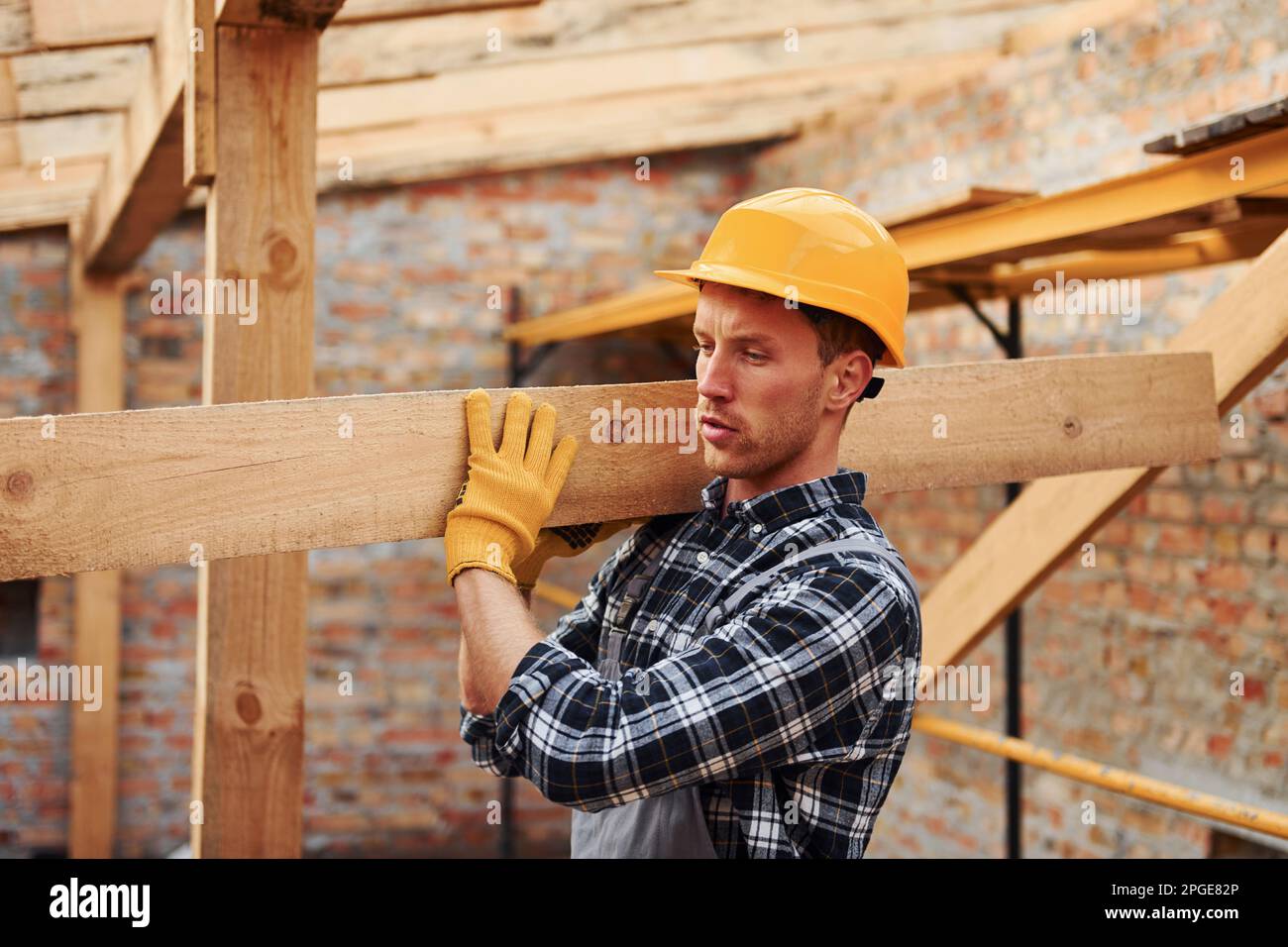 Transporting wooden boards. Construction worker in uniform and safety