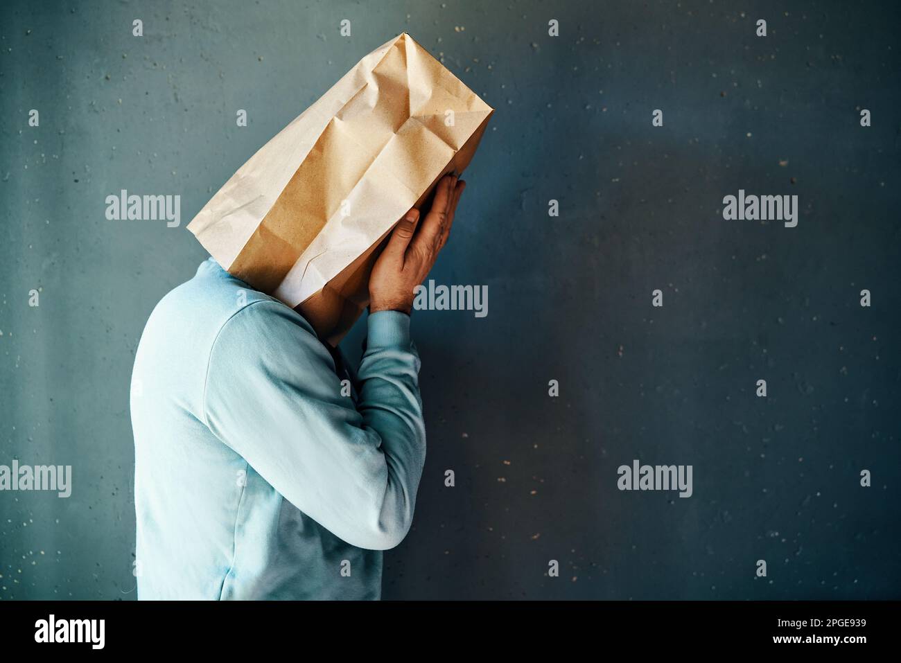 Upset man with a paper bag on head covering eyes with both hands. Profile view, copy space. People emotion concept Stock Photo