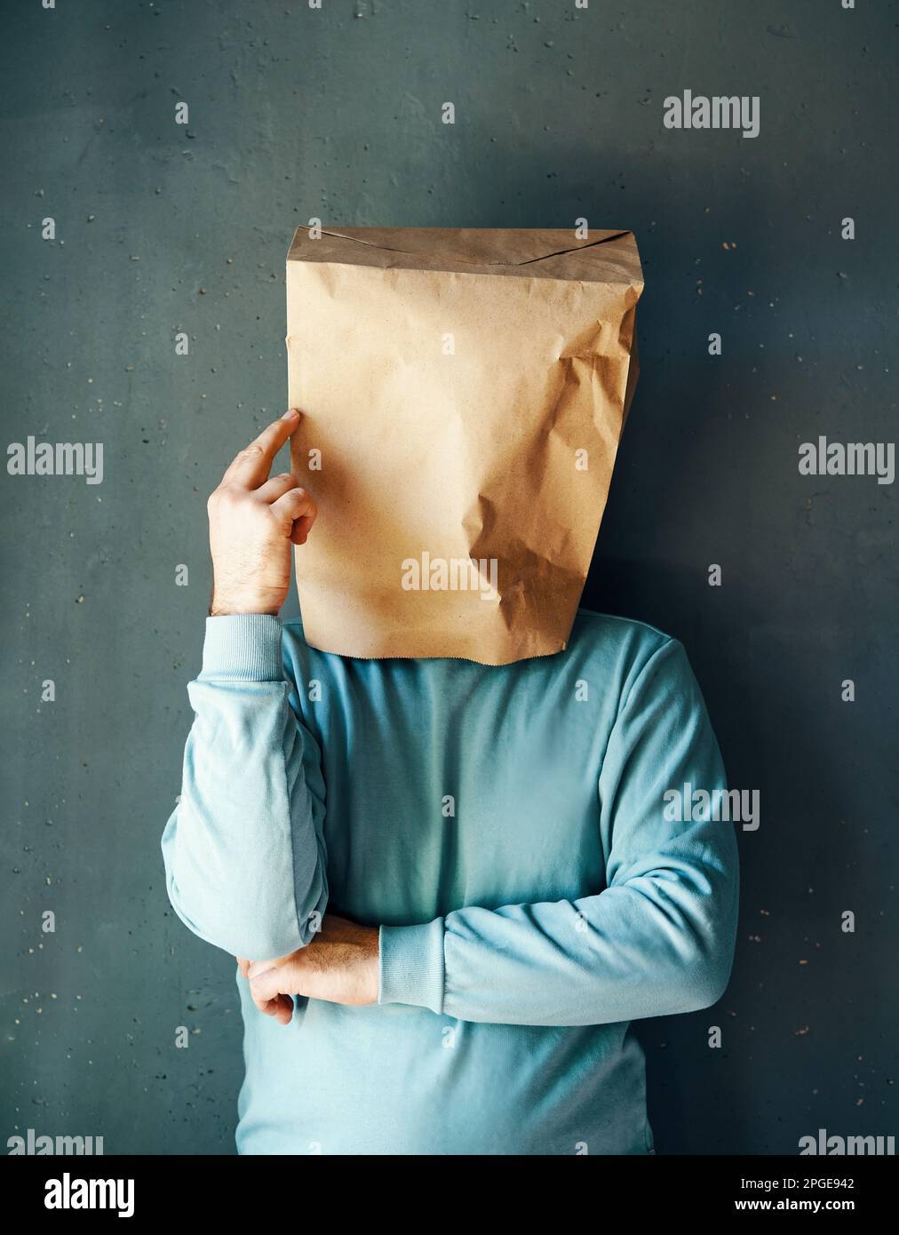 Man with a paper bag on head pointing to head with one finger. Great