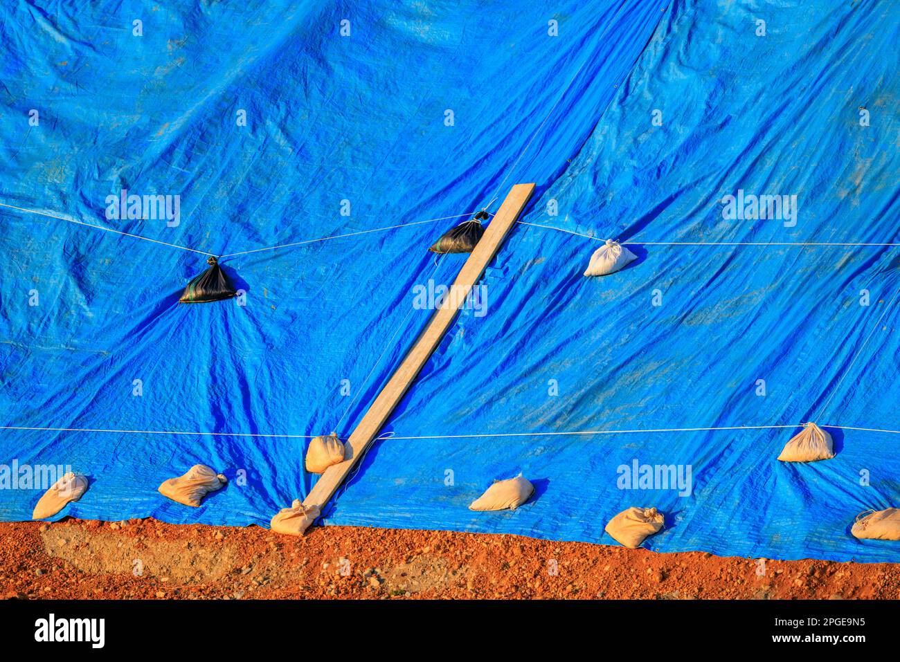 Blue tarp secured with sandbags protects materials from weather