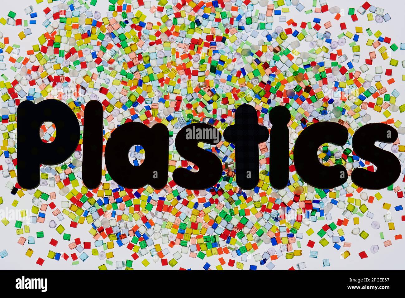 dumped heap of multicolored plastic resin granulates on white background with font letters Plastic Stock Photo