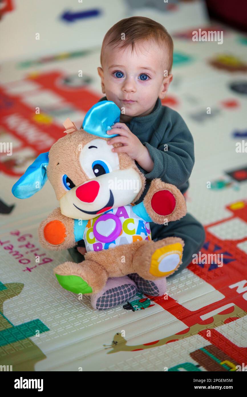 9 month old baby boy sitting on a playmat holding a plush toy Stock Photo Alamy