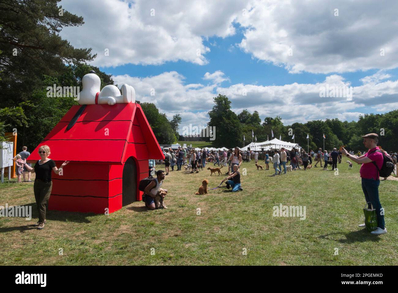 People taking selfies with their dogs standing in front of a massive red kennel with Snoopy lying on top at Goodwoof, The Kennels, Goodwood,Sussex, UK Stock Photo