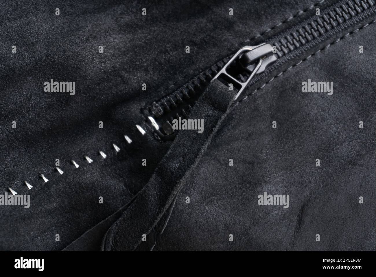 Zip with a tab on a black suede jacket with white contrasting seams background close up Stock Photo