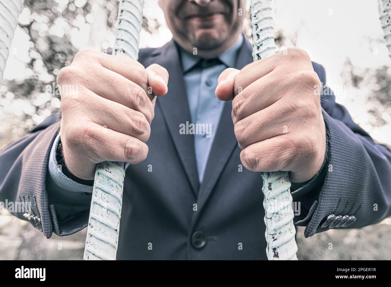 Hands of a young adult businessman through bars of a prison cell in a derelict building. concept of financial crimes Stock Photo