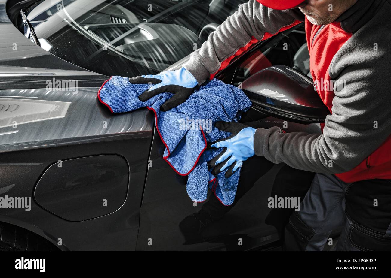 Professional Car Wash Worker Cleaning Vehicle Body Using Soft Cloth. Automotive Detailing Job. Stock Photo