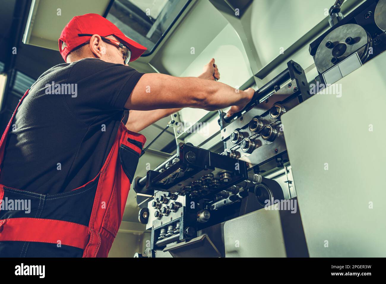 Modern Automatic Metalworking Wire Bending Machine Operator In Front of the Machinery. Stock Photo