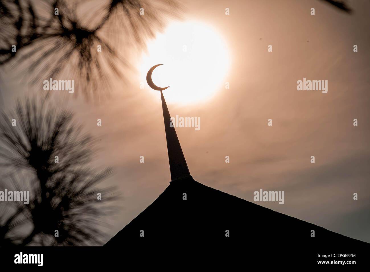 A silhouette of a replica crescent moon against the sun during a 'rukyah', a moon sighting ceremony to determine the start date of the holy month of Ramadan in Bukit Malawati. Stock Photo