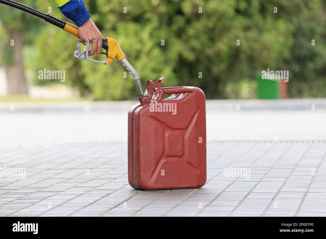 A man fills jerry cans at a gas station. A man fills gasoline in a canister at a gas station