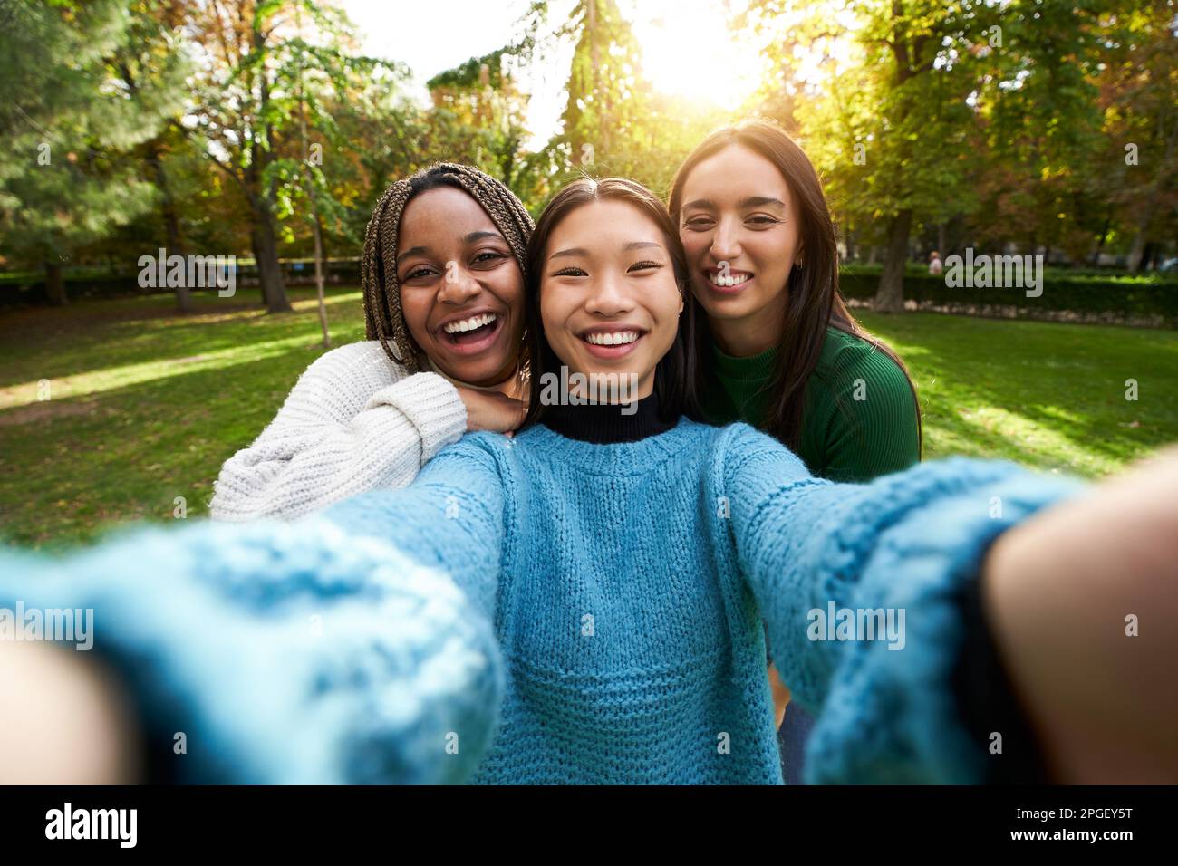 Portrait three smiling girls posing outdoor photo looking at camera. Multi-ethnic group of people.  Stock Photo