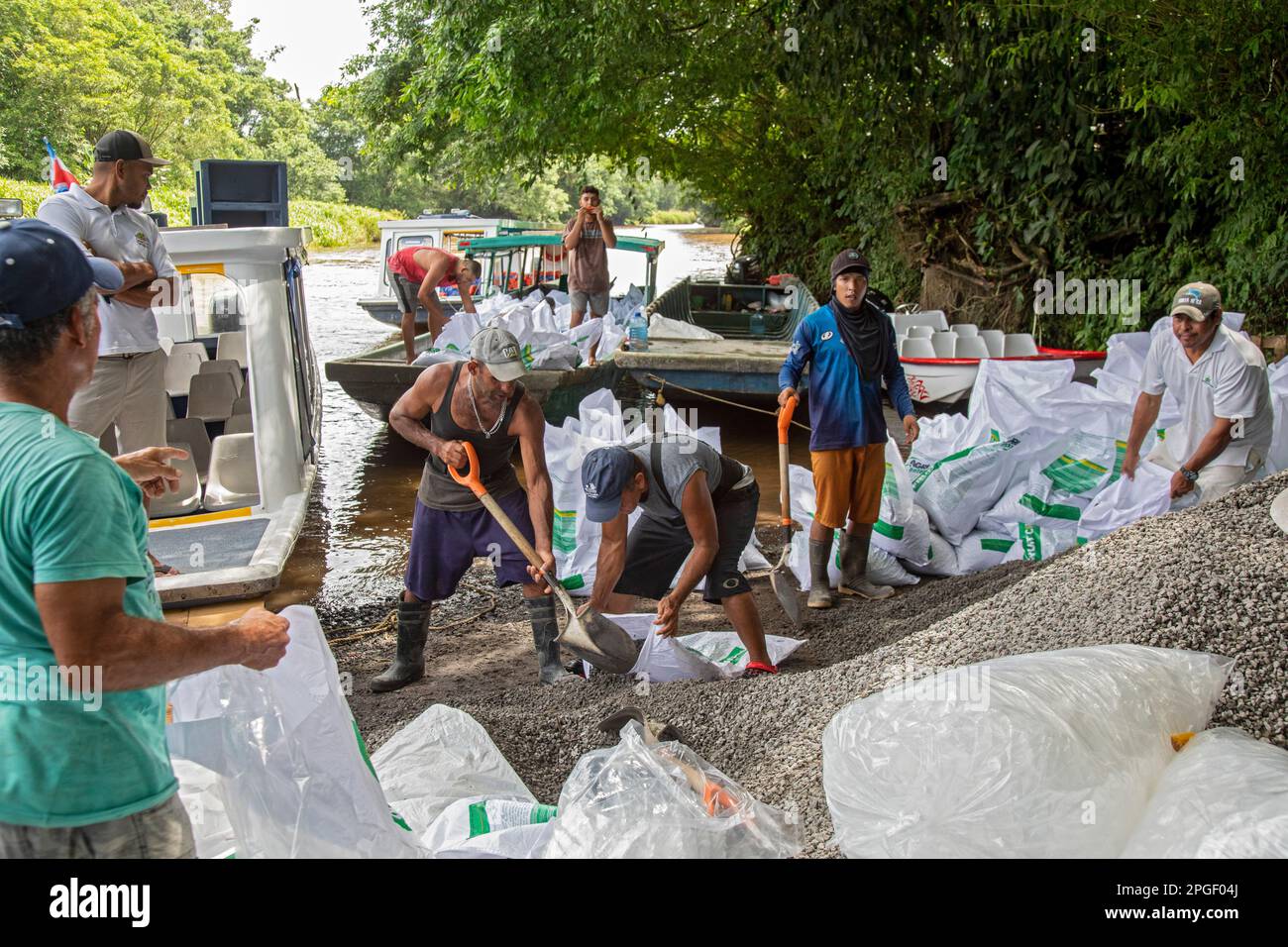 La Pavona, Costa Rica - Workers load gravel for a construction project onto a boat on the Suerte River for the hour-long trip to the town of Tortuguer Stock Photo