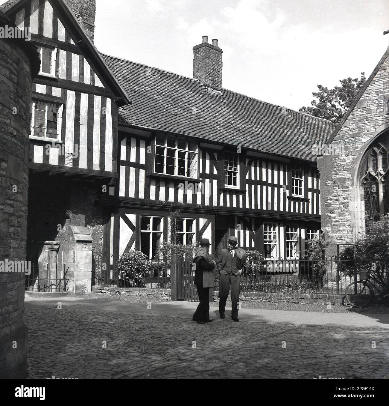 1950s, historical, two men talking outside The Old Vicarage, an old timber-framed building, in Evesham, Wychavon, Worcestershire, England, UK. The Church House was listed as a Grade II building in 1952. Stock Photo