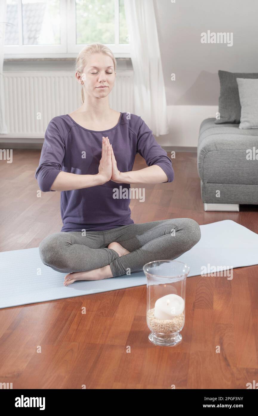 Young woman doing lotus pose yoga on exercise mat in living room, Bavaria,  Germany Stock Photo - Alamy