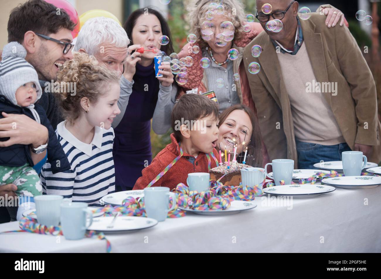 Little boy blowing out candles on his cake at his birthday party