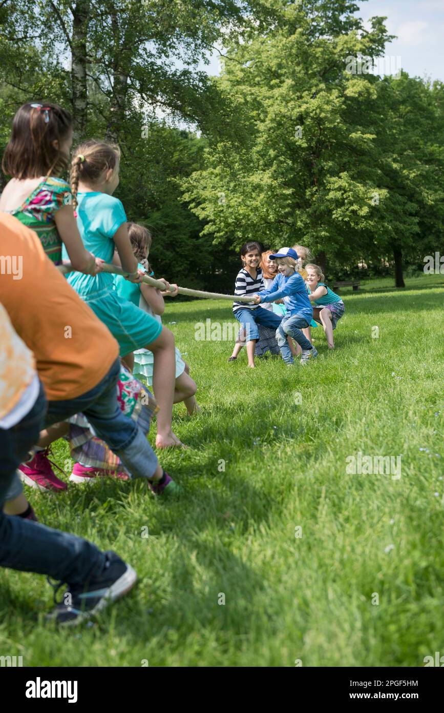Group of children playing tug-of-war in a park, Munich, Bavaria, Germany Stock Photo