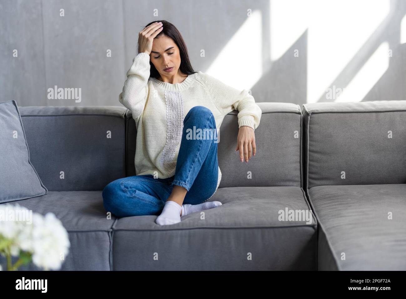 Depressed sad attractive woman crying on sofa couch at home feeling lonely tired and worried suffering depression in mental health Stock Photo