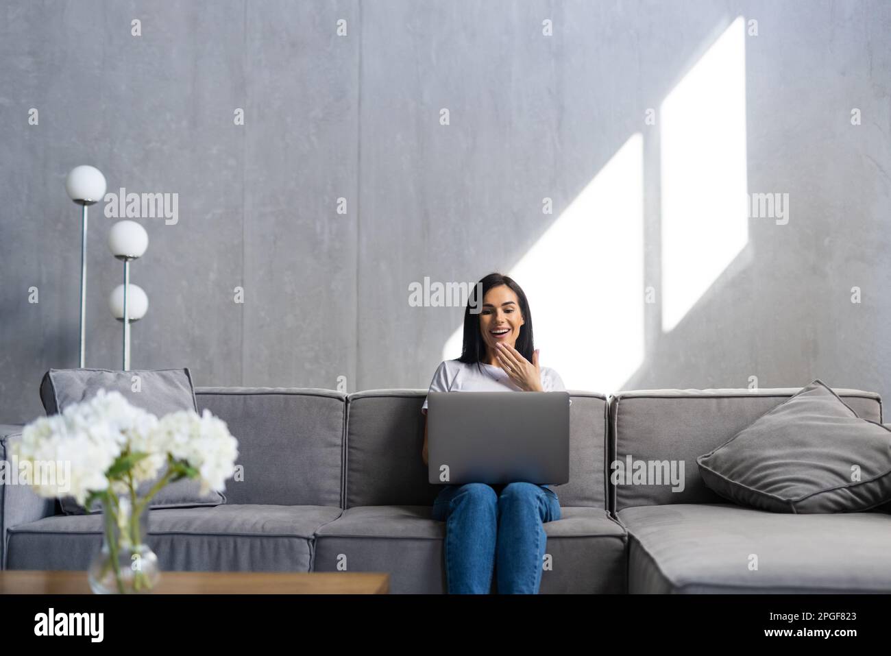 Woman using a laptop while relaxing on the couch Stock Photo