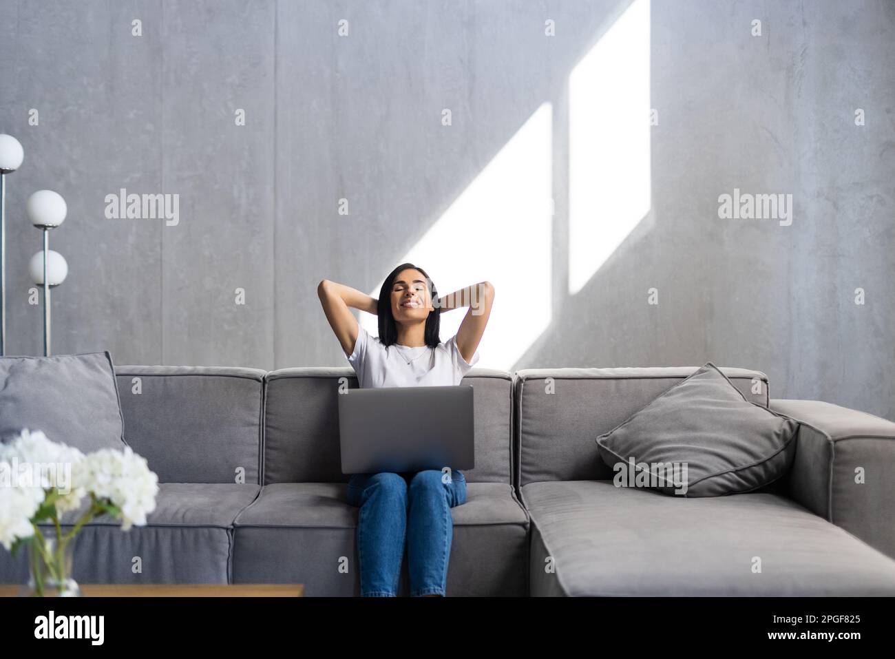 Happy woman with credit card and laptop sitting on sofa at home Stock Photo