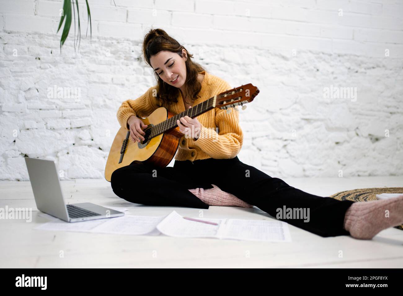Beautiful young woman playing the guitar at home Stock Photo