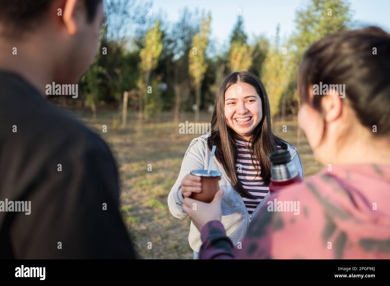 Close Up Of Smiling Friends Drinking Yerba Mate Using A Thermos With Hot  Water In The Countryside At Sunset Stock Photo - Download Image Now - iStock