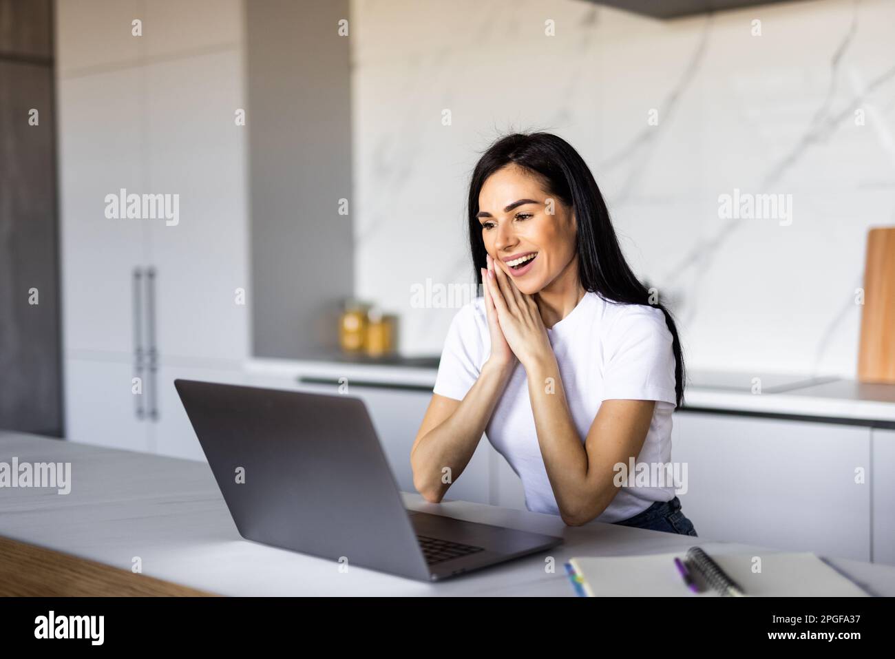Cute smiling woman using laptop at home. Student girl working on computer. Stock Photo