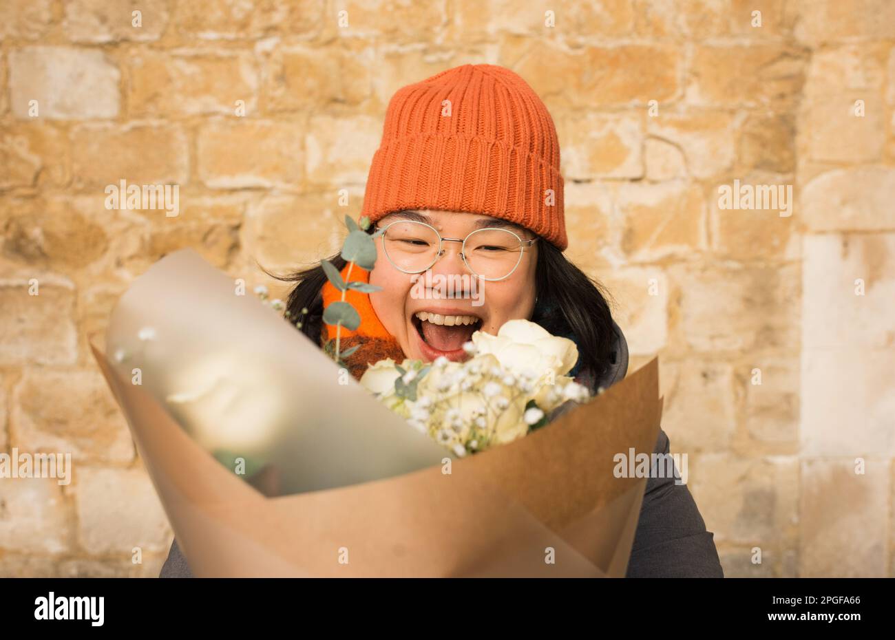 Asian woman holding a big bunch of flowers smiling Stock Photo