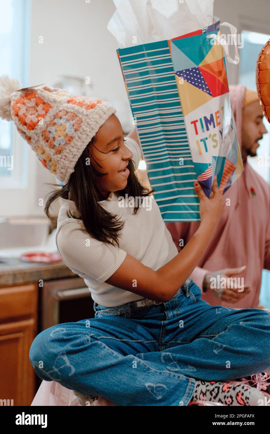 preteen opening birthday presents with family Stock Photo