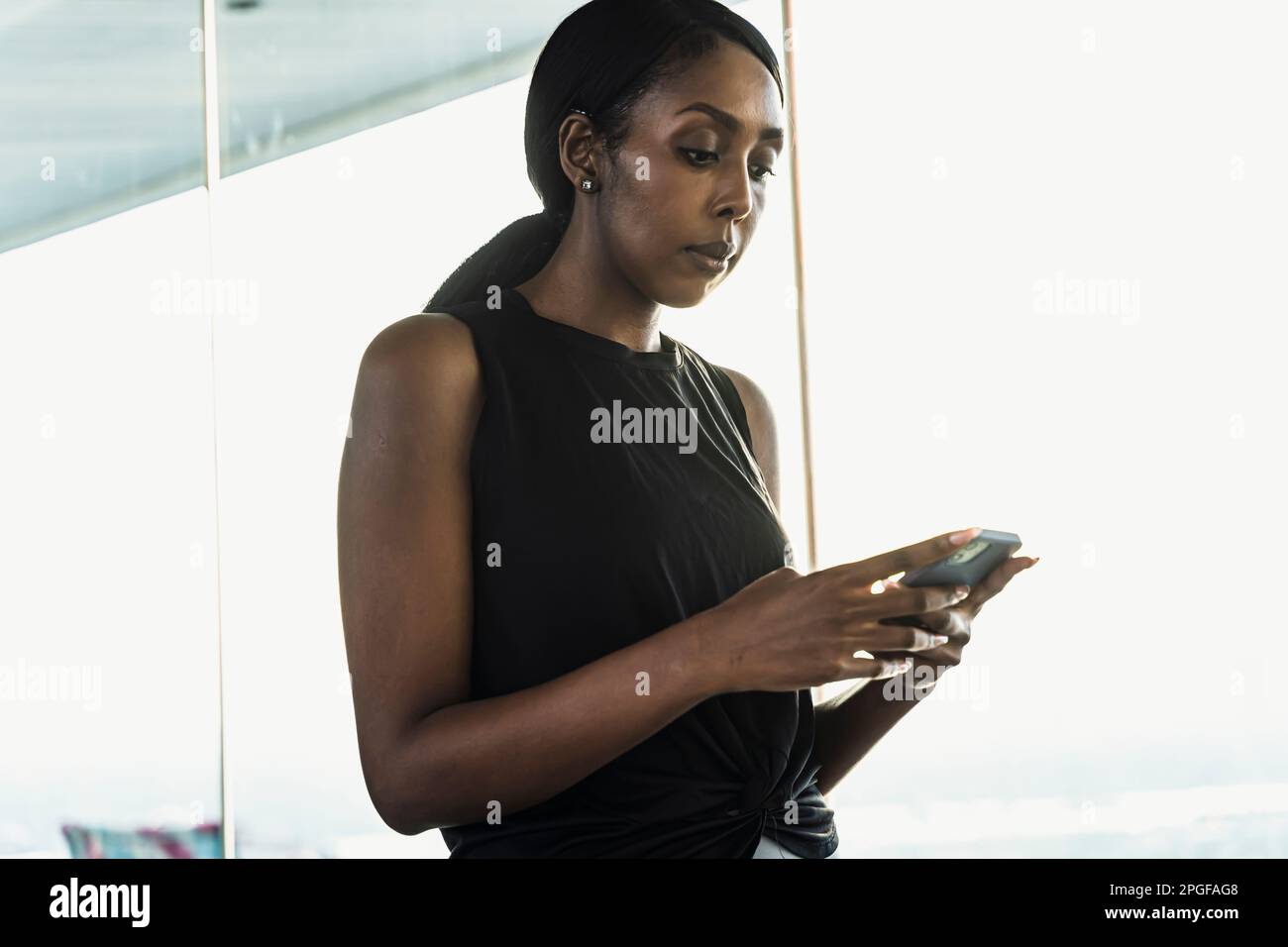 Athletic black woman using her mobile phone outdoors. Stock Photo