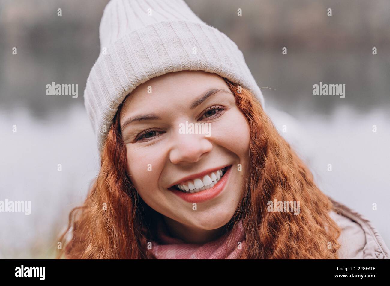 Curly redhead woman 30-35 in hat smiling Stock Photo