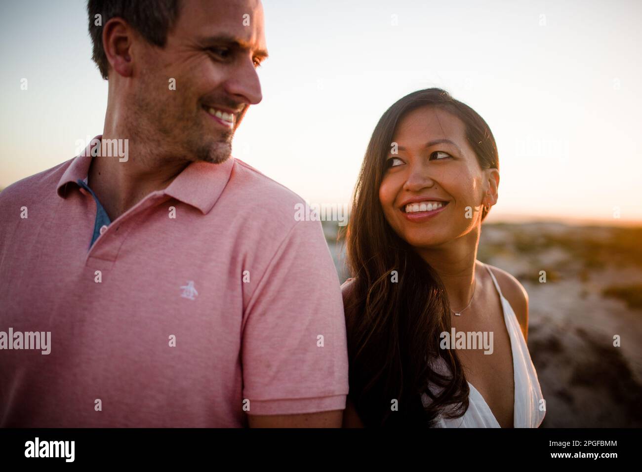 Husband & Wife Smiling at One Another on Beach in San Diego Stock Photo