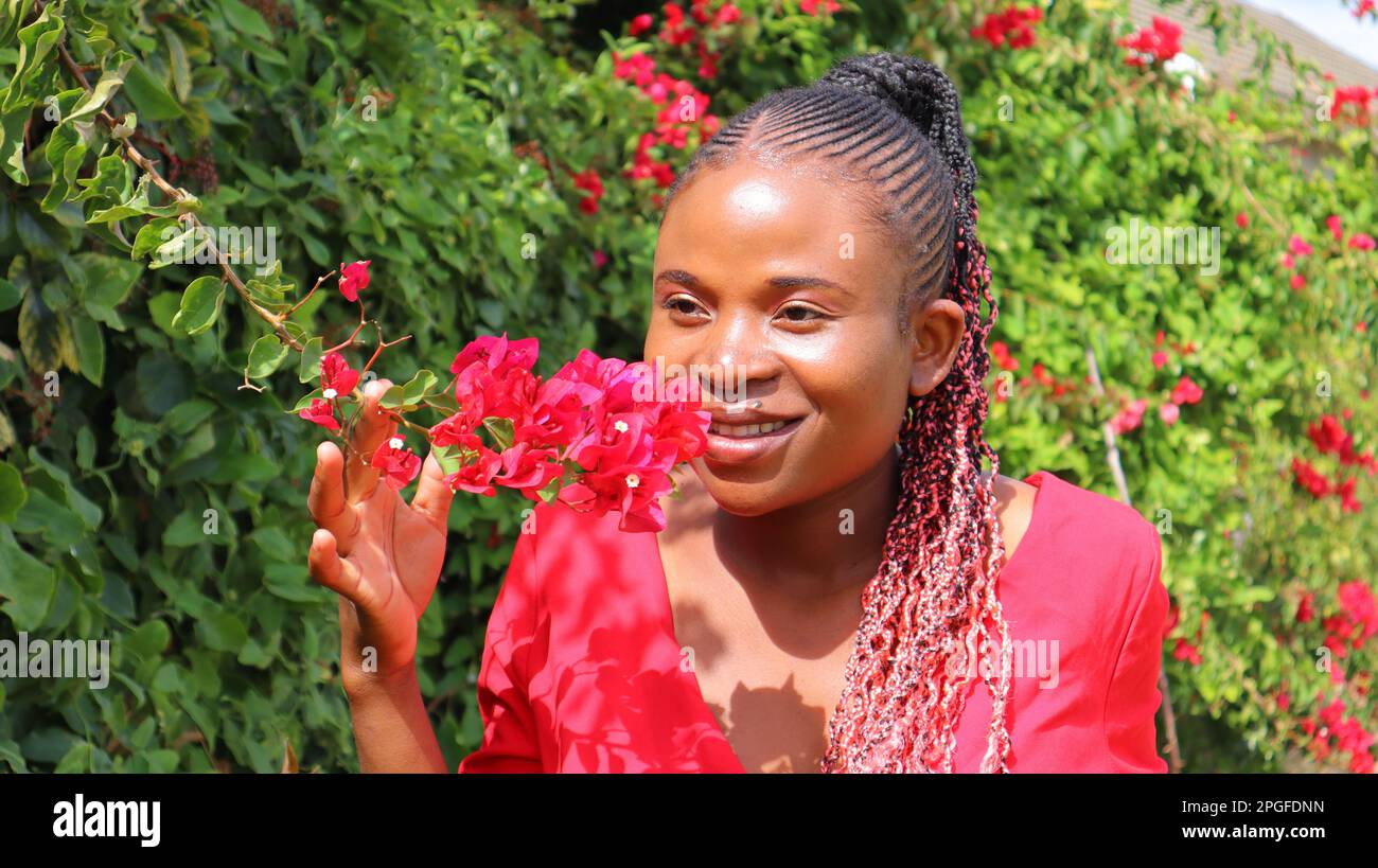black African woman smelling flowers and smiling Stock Photo Alamy