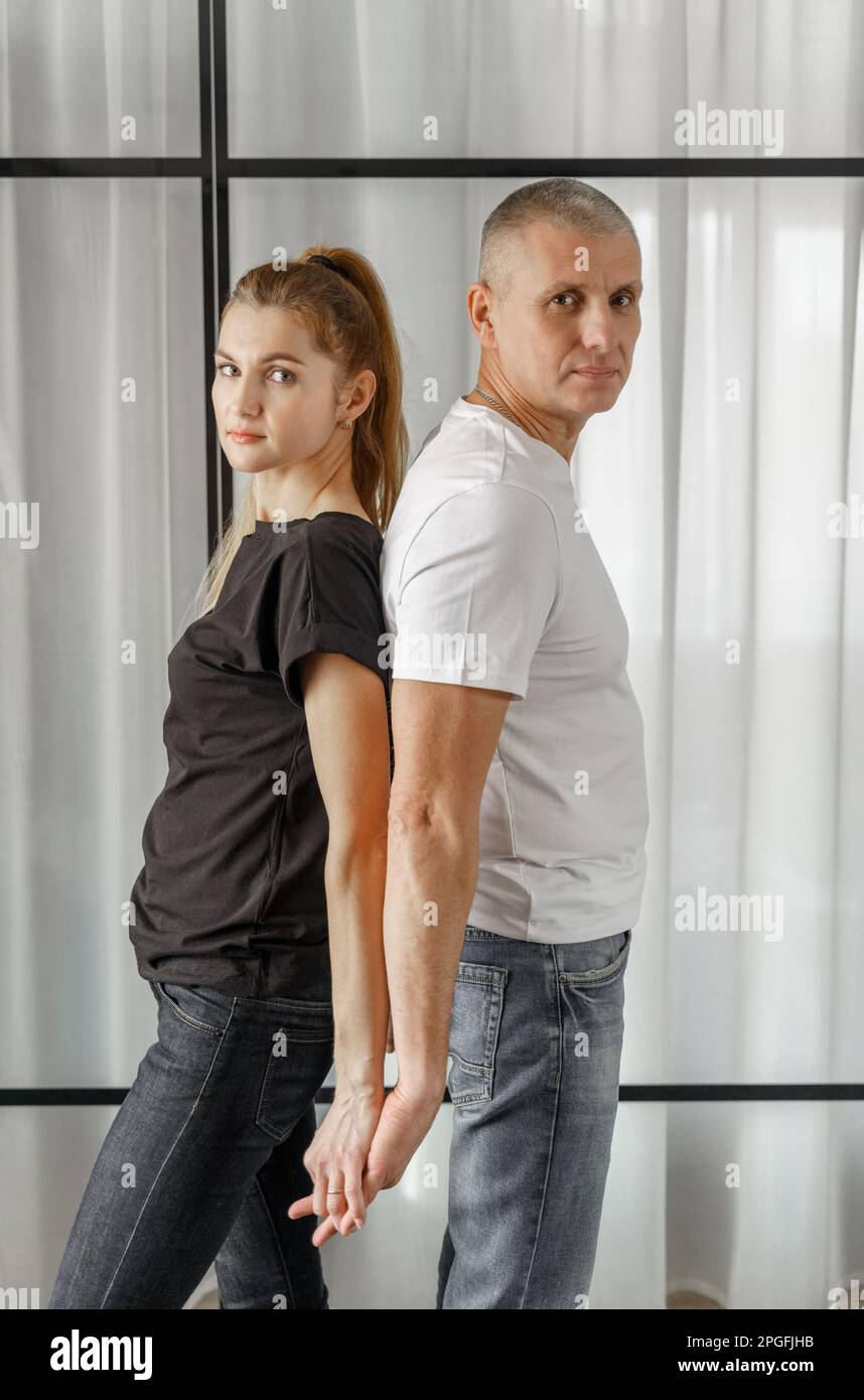 Portrait of a happy married couple who stand back to back holding hands