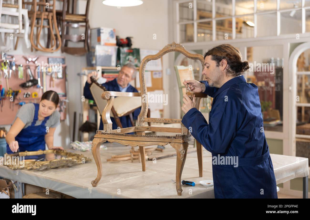 man restorer spackling antique chair surface getting piece of furniture ready for further coloring Stock Photo