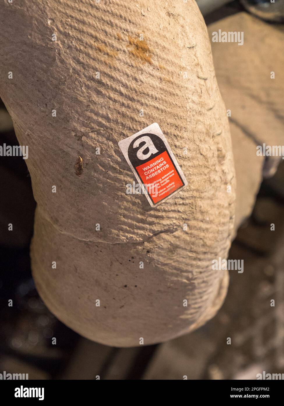 'Warning Contains Asbestos' label on pipe lagging inside the RNLI Historic Lifeboat Collection, Historic Dockyard Chatham, Kent, UK. Stock Photo